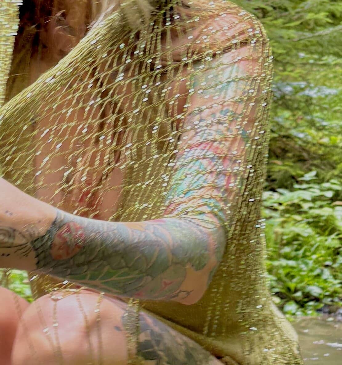 Close-up of the knotted gold mesh across a shoulder, sequins catching the light.